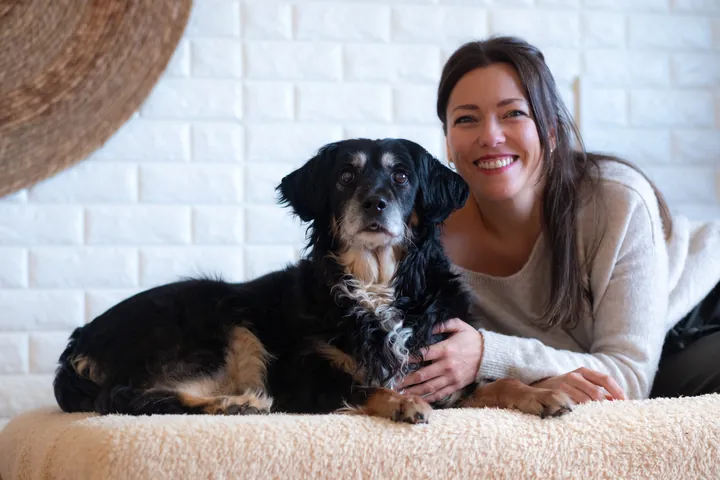 Mery Calvo sonriendo tumbada junto a su perra Noa